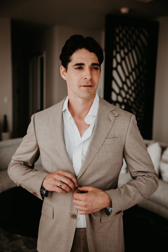 Groom prepares and gets dressed in his tan suit before his wedding in the Virgin Islands