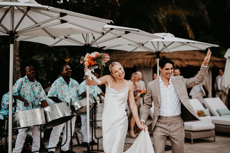 The bride and groom enter their reception together for their wedding in the Virgin Islands with a line of steel drum players behind them.