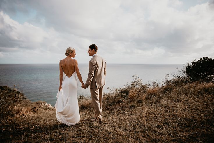 Bride and groom hold hands while looking out at their wedding in the Virgin Islands