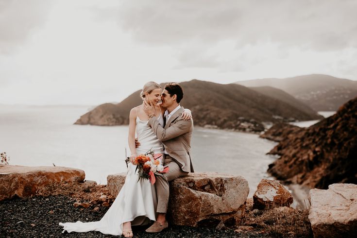 A couple sitting together on a rock with the ocean behind them during their wedding in the Virgin Islands.