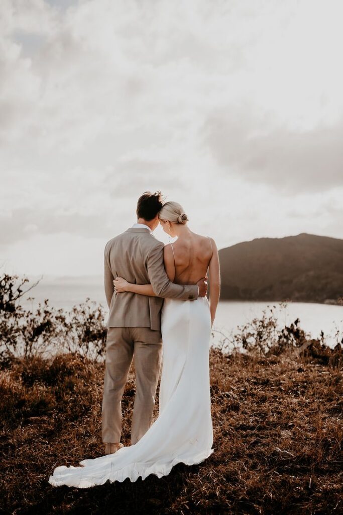 Bride and groom hold hands while looking out at their wedding in the Virgin Islands