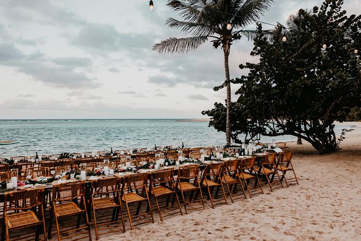 A long set of table and chairs sits on sand for the reception of a wedding in the Virgin Islands